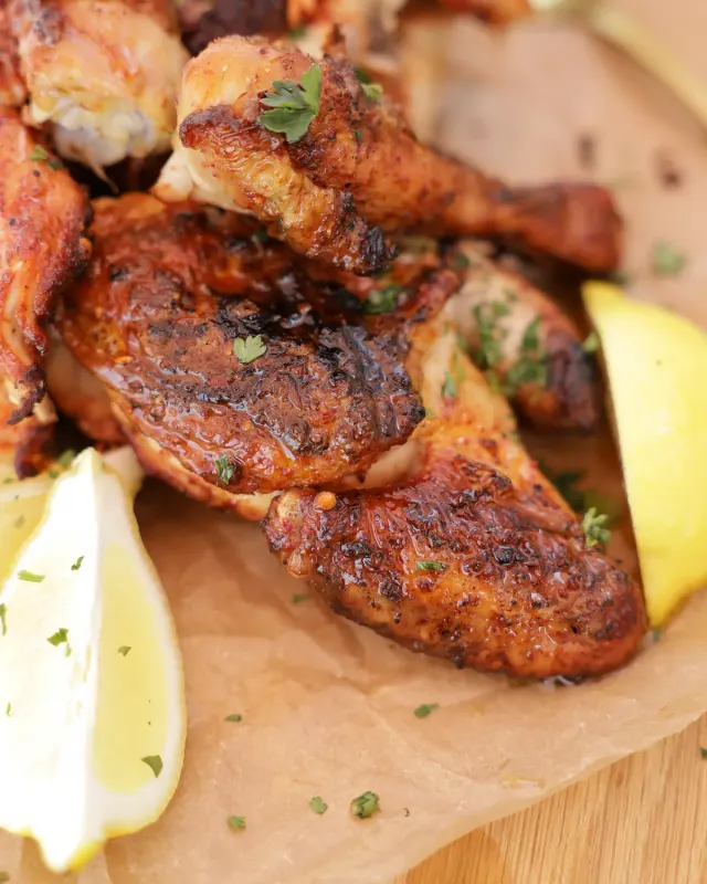 Peri-peri chicken pieces with lemon wedges on baking paper - Parreirinha Rapido Illovo